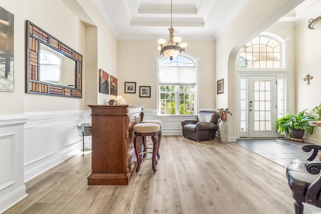 living area featuring ornamental molding, light wood-type flooring, plenty of natural light, and a tray ceiling