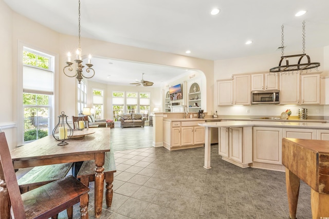 kitchen featuring ceiling fan, cream cabinets, decorative light fixtures, and plenty of natural light