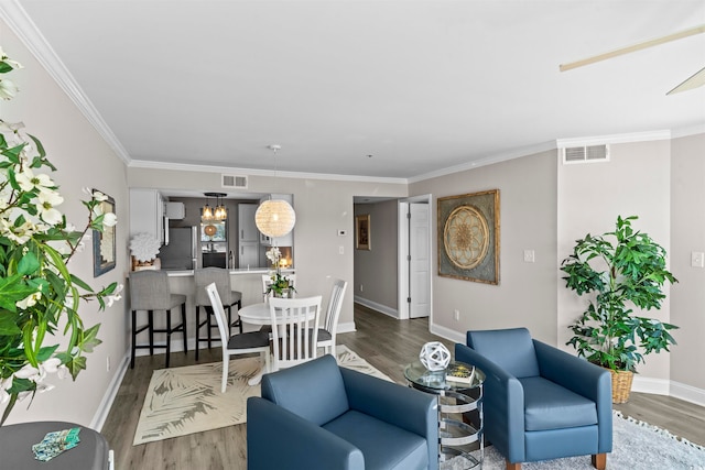 living room featuring crown molding, hardwood / wood-style floors, and an inviting chandelier