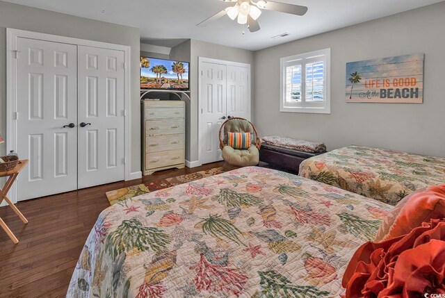 bedroom with ceiling fan, multiple closets, and dark hardwood / wood-style flooring