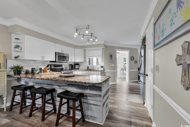 kitchen featuring white cabinets, stainless steel appliances, kitchen peninsula, and a breakfast bar