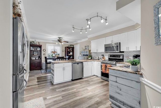 kitchen featuring appliances with stainless steel finishes, kitchen peninsula, light stone countertops, and white cabinets