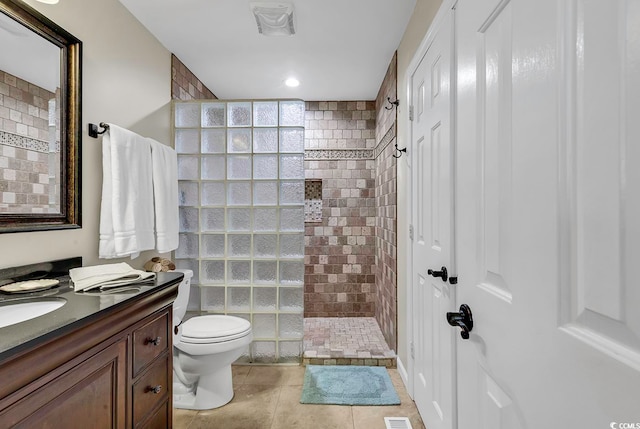 bathroom with tile patterned floors, toilet, tiled shower, and vanity