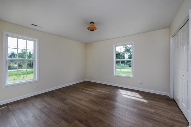 unfurnished bedroom with multiple windows, a closet, and dark hardwood / wood-style flooring