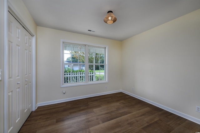 unfurnished bedroom with a closet and dark hardwood / wood-style flooring