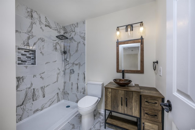 bathroom featuring vanity, toilet, and tiled shower