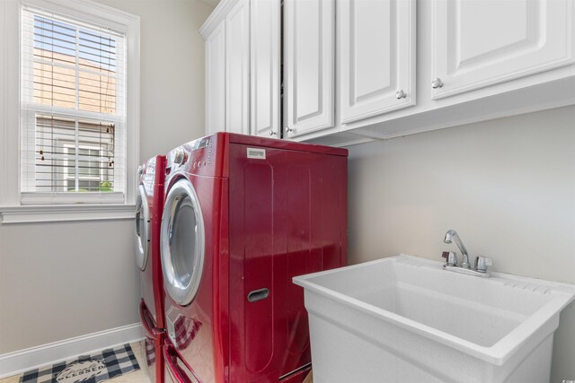 washroom featuring a wealth of natural light, separate washer and dryer, sink, and cabinets