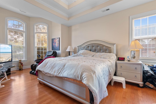 bedroom featuring ornamental molding, light hardwood / wood-style floors, and multiple windows