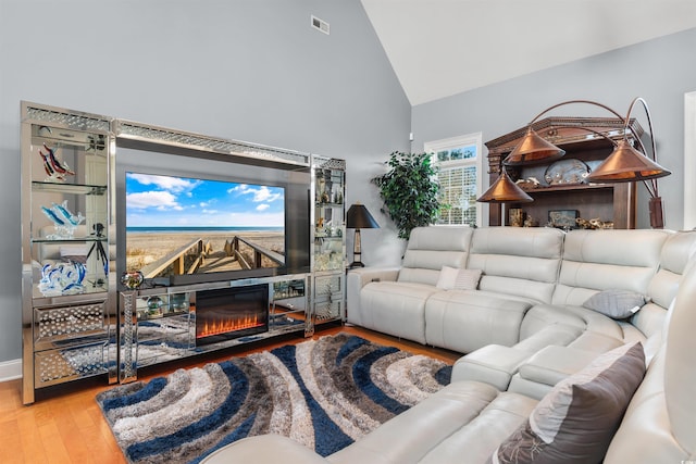 living room with high vaulted ceiling and light hardwood / wood-style flooring