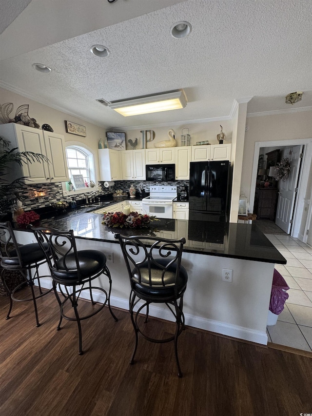 1538 Lanterns Rest Rd Unit 303, Myrtle Beach, SC 29579 - kitchen featuring black appliances, a textured ceiling, dark countertops, a kitchen bar, and tasteful backsplash