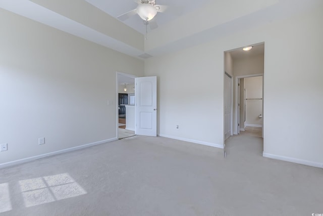 unfurnished bedroom with ceiling fan, ensuite bath, and light colored carpet