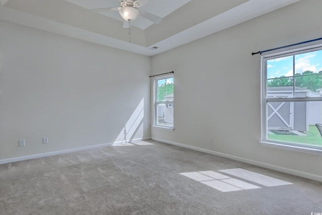 carpeted empty room with ceiling fan and a raised ceiling