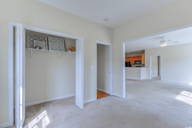 interior space with a closet, ceiling fan, black fridge, and light carpet