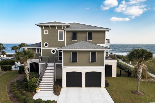 view of front of home with a garage, a water view, and a front lawn