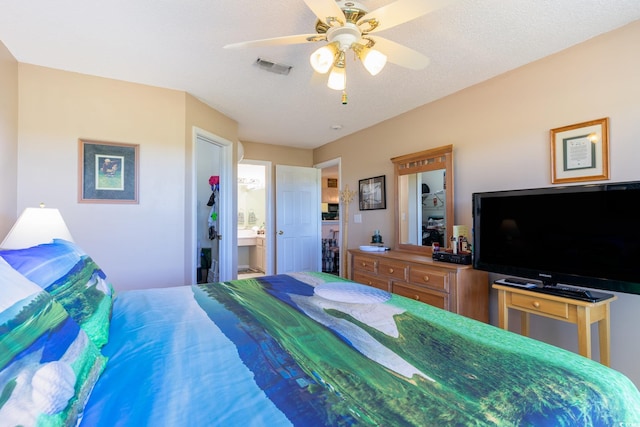 bedroom with ceiling fan, connected bathroom, and a textured ceiling