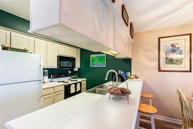 kitchen featuring hardwood / wood-style floors, white appliances, sink, a breakfast bar area, and a textured ceiling