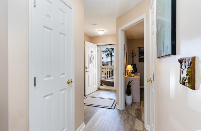 hall with a textured ceiling and light hardwood / wood-style floors