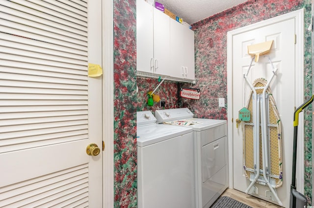 laundry area with cabinets, washing machine and dryer, and a textured ceiling