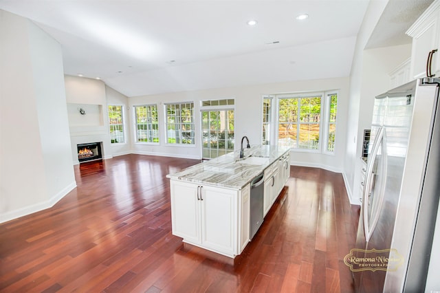 kitchen with white cabinets, white fridge with ice dispenser, an island with sink, and plenty of natural light