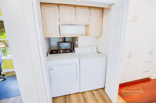 clothes washing area featuring cabinets, light hardwood / wood-style floors, and washer and clothes dryer