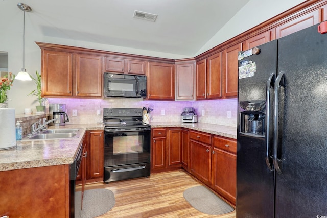 kitchen featuring sink, black appliances, light hardwood / wood-style floors, hanging light fixtures, and lofted ceiling