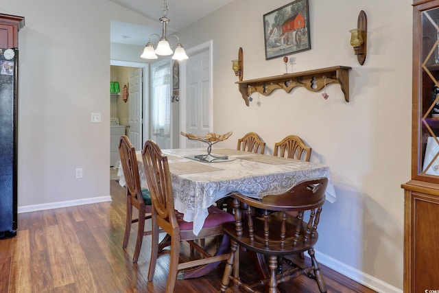 dining space featuring washer / clothes dryer, a chandelier, and dark hardwood / wood-style floors