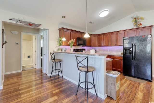 kitchen featuring hanging light fixtures, kitchen peninsula, wood-type flooring, lofted ceiling, and black appliances