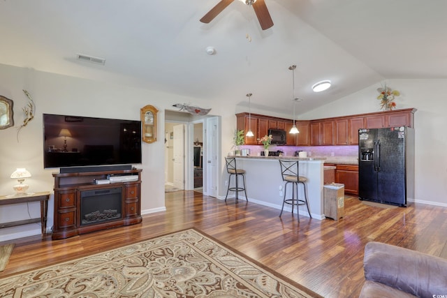 living room featuring ceiling fan, wood-type flooring, and lofted ceiling