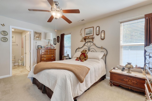 bedroom featuring ceiling fan, ensuite bathroom, and light carpet