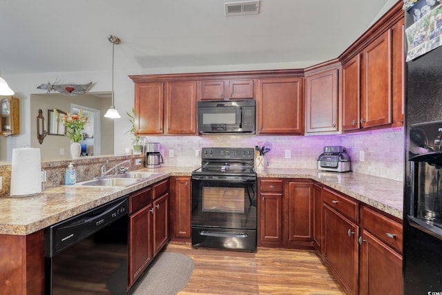 kitchen with pendant lighting, black appliances, sink, light hardwood / wood-style flooring, and kitchen peninsula