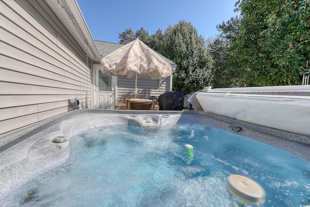 view of pool with area for grilling and a hot tub