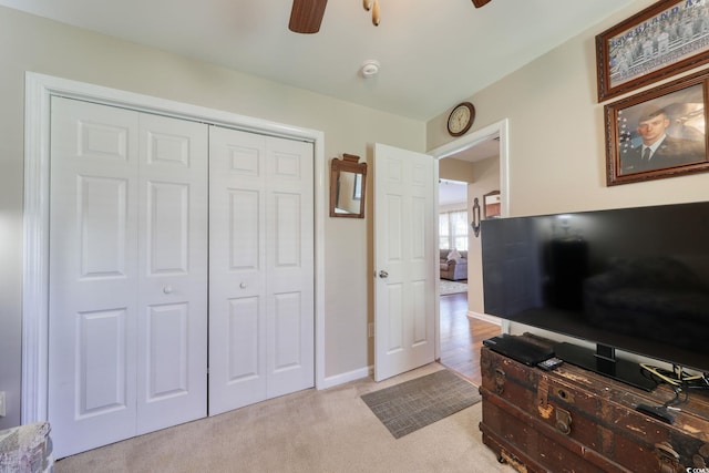 bedroom with ceiling fan, light carpet, and a closet