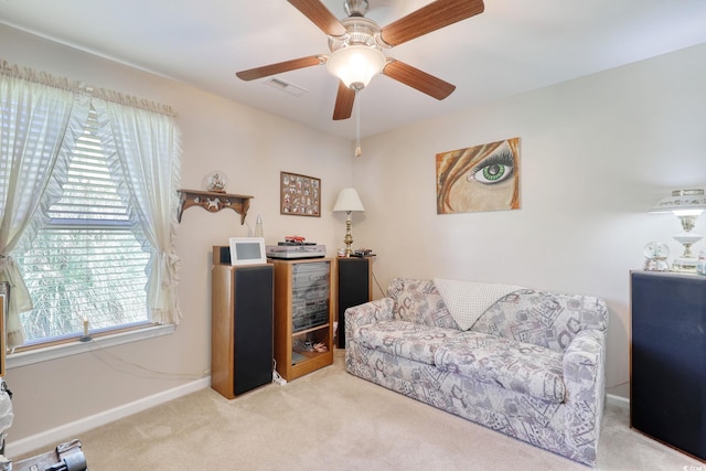 living area with light carpet and ceiling fan