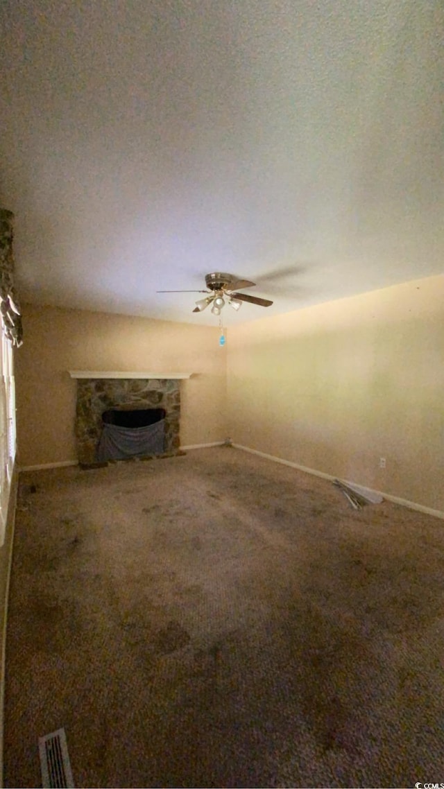 unfurnished living room featuring a stone fireplace, carpet floors, and a textured ceiling