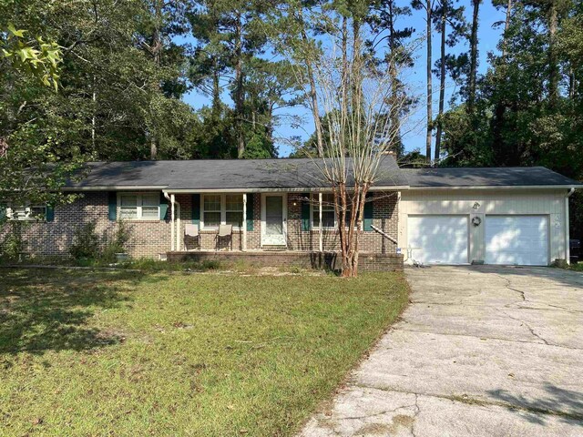 single story home featuring a garage, covered porch, and a front lawn