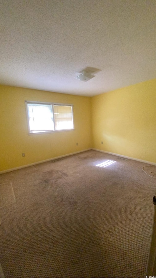 carpeted empty room featuring a textured ceiling