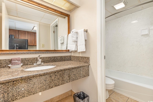 full bathroom featuring washtub / shower combination, a drop ceiling, sink, tile patterned flooring, and toilet