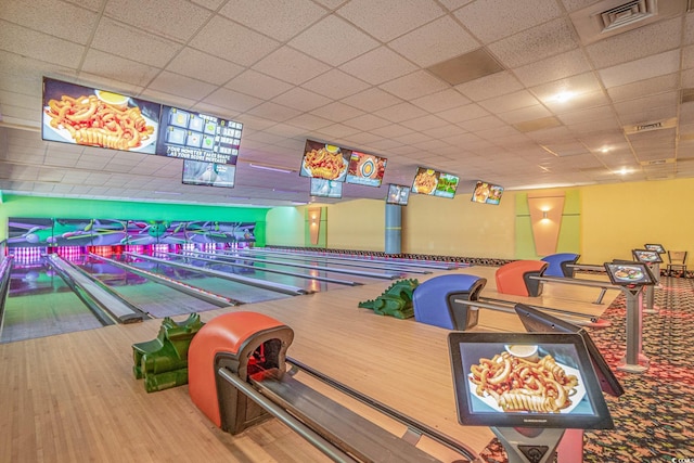 recreation room with bowling, a drop ceiling, and hardwood / wood-style flooring