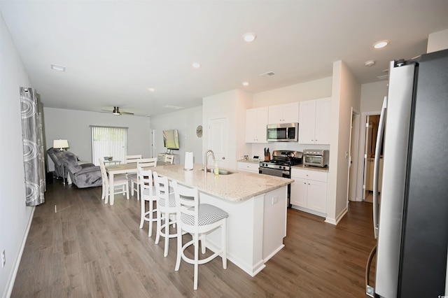 kitchen with stainless steel appliances, an island with sink, sink, and white cabinets