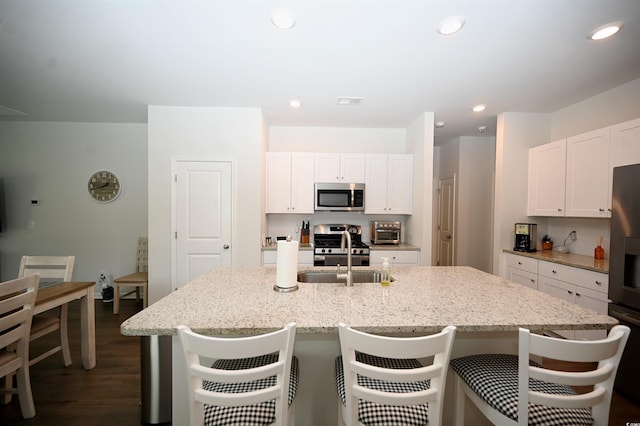 kitchen featuring stainless steel appliances, sink, a center island with sink, and white cabinets