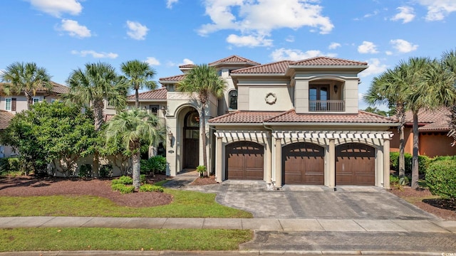 mediterranean / spanish-style house with a tiled roof, stucco siding, decorative driveway, a garage, and a balcony