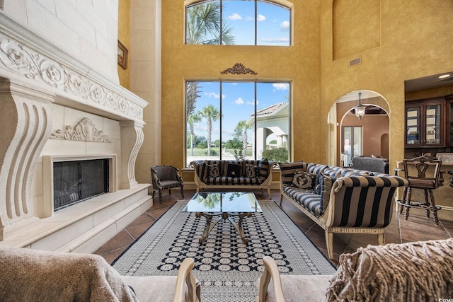 living room with tile patterned floors, visible vents, arched walkways, and a tile fireplace