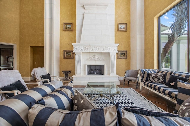 living area featuring a wealth of natural light, a fireplace, a high ceiling, and decorative columns