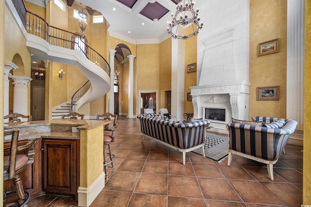 living area with coffered ceiling, ornate columns, a fireplace, ornamental molding, and stairs