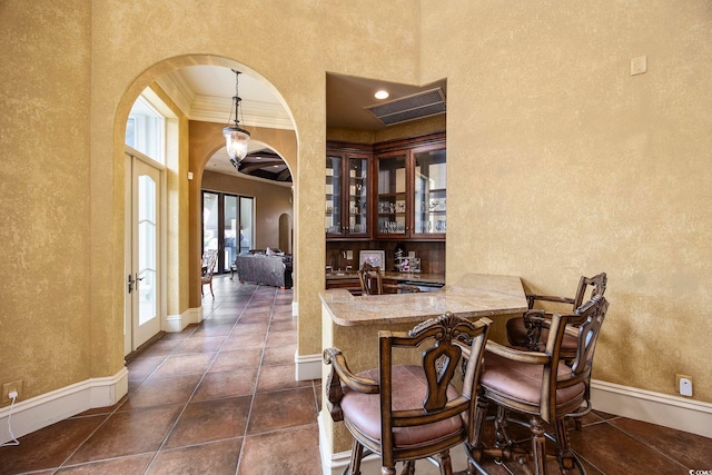 dining space with visible vents, baseboards, ornamental molding, arched walkways, and dark tile patterned flooring