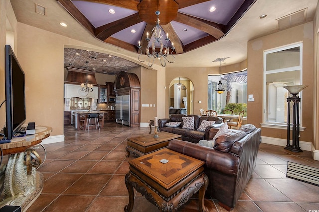 living area featuring an inviting chandelier, dark tile patterned floors, visible vents, and arched walkways