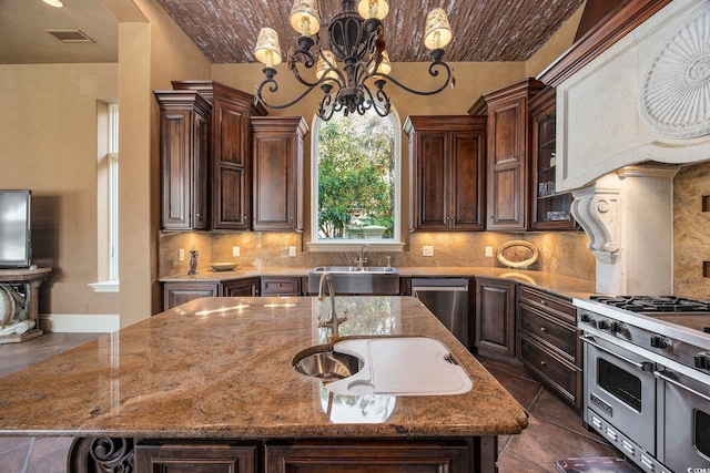 kitchen featuring a notable chandelier, appliances with stainless steel finishes, decorative backsplash, and a sink