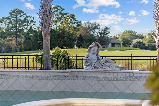 surrounding community featuring view of golf course, a yard, and fence