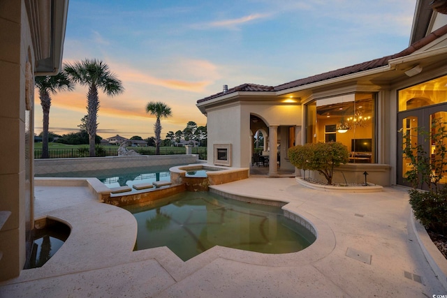 view of pool with fence, a pool with connected hot tub, and a patio area