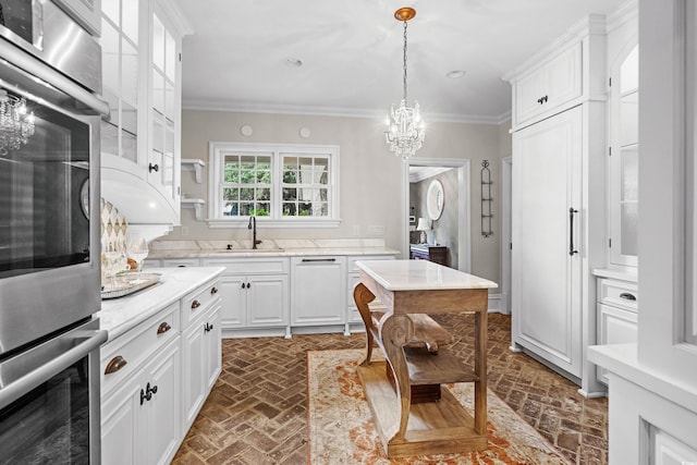 kitchen with double oven, white dishwasher, sink, crown molding, and white cabinets